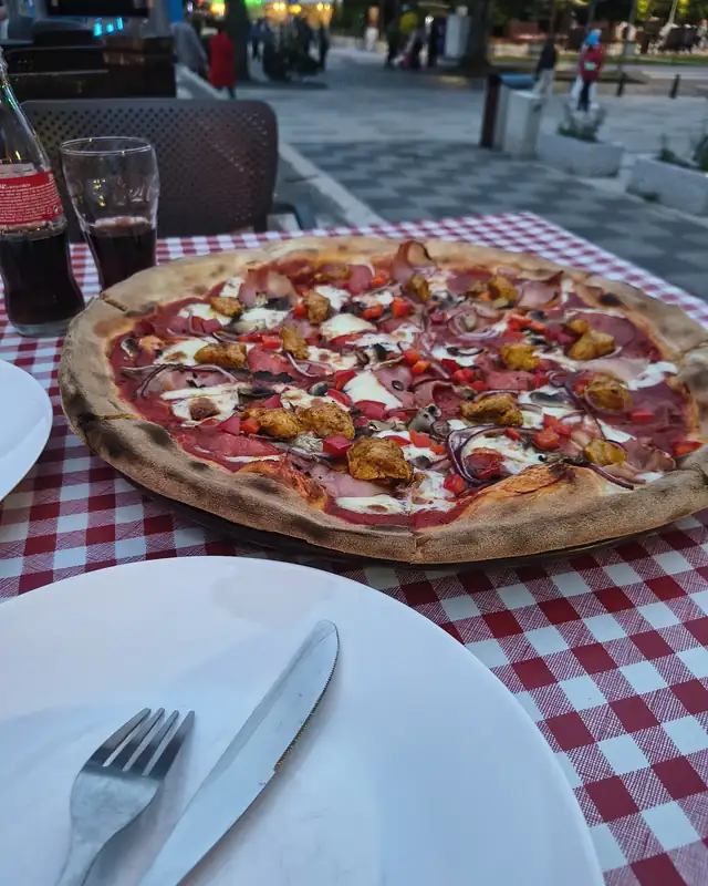 Pizza na stoliku w ogródku, w tle ulica