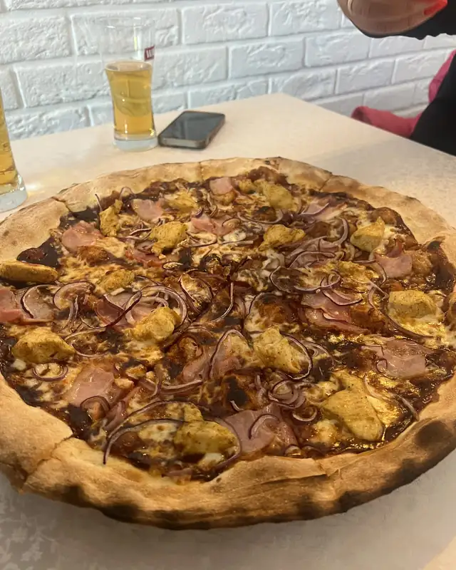 Pizza z boczkiem i kukurydzą na stole w ogródku