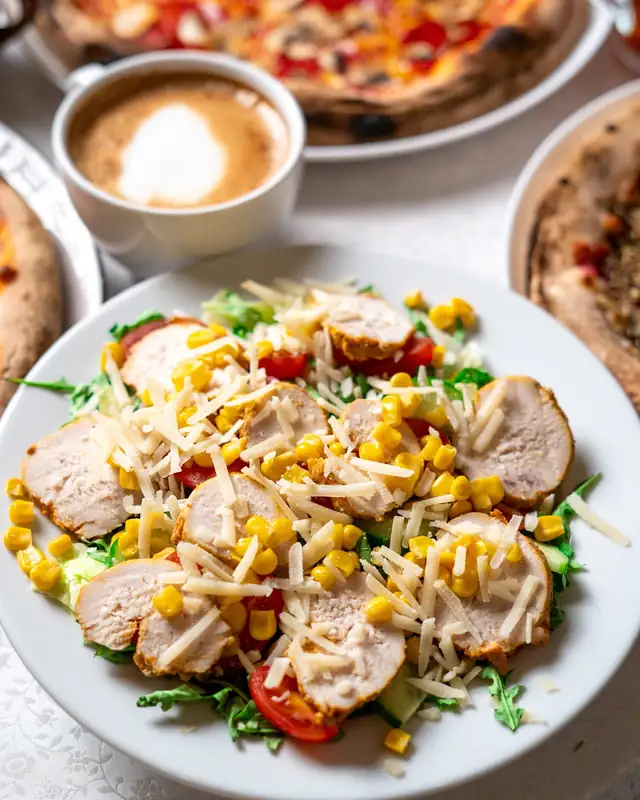 Sałatka z kurczakiem, obok kawa i pizza