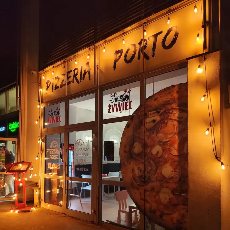 Wieczorem: podświetlony szyld PIZZERIA PORTO z girlandą żarówek nad witryną